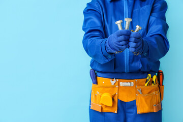 Mechanic with tools holding bolts on blue background