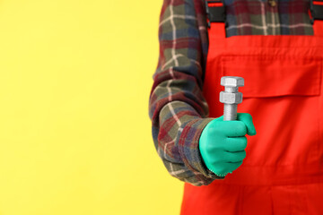 Mechanic with bolt on yellow background