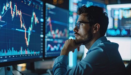 A focused individual monitoring the stock market trends on multiple computer screens, analyzing financial data