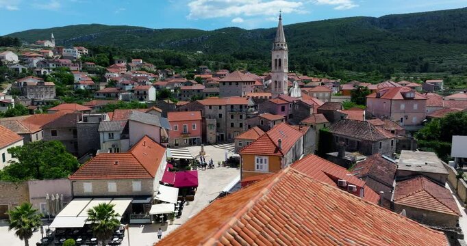 Tiled Roofs Of Houses In Jelsa Town With Bell Tower Of Church In Hvar Island, Croatia. - aerial shot