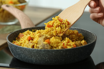 Woman frying pilaf in kitchen, closeup
