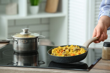 Woman frying pilaf on stove in kitchen, closeup