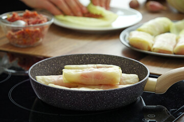 Frying pan with stuffed cabbage rolls on stove in kitchen, closeup