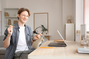 Teenage boy with laptop and headset working online at home