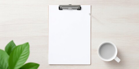 Blank clipboard on wooden desk with coffee and green plant