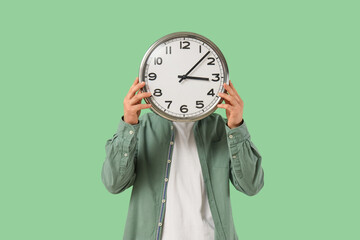 Man with wall clock on green background
