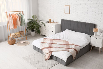 Interior of bedroom with clothes rack, commode and table