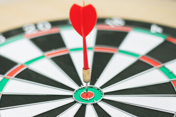 Dart arrow hitting in the target center of dartboard
