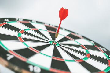 Dart arrow hitting in the target center of dartboard
