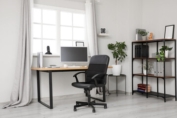Interior of office with desk, black chair and shelf unit