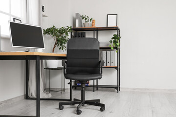 Interior of office with desk, black chair and shelf unit