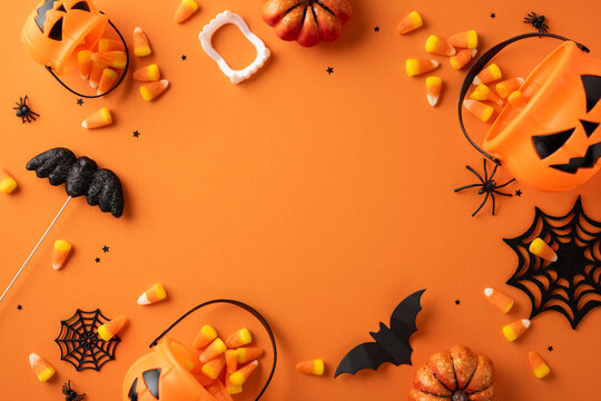 Halloween-themed items including candy corn, pumpkins, bats, spider webs, and jack-o'-lanterns arranged creatively on an orange background for a festive holiday theme - Powered by Adobe