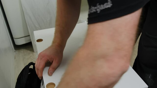 Professional inspects surface before creating final structure. Furniture assembler turns large wooden object over and places item in horizontal position