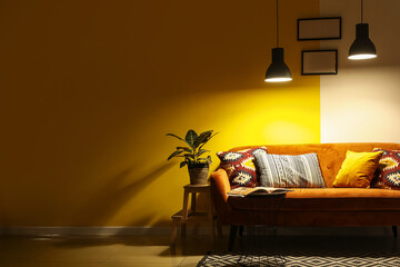 Interior of dark living room with red sofa, table and glowing lamps