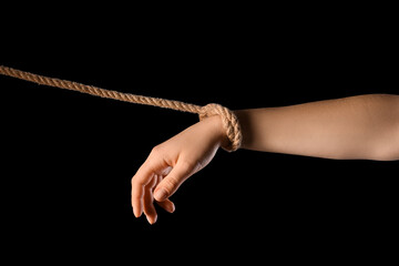 Hand with rope on black background. Concept of oppression