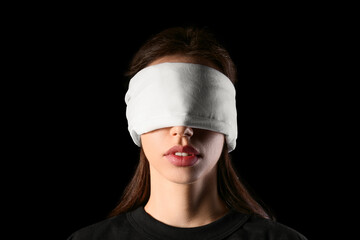 Young woman with blindfold on black background. Concept of oppression