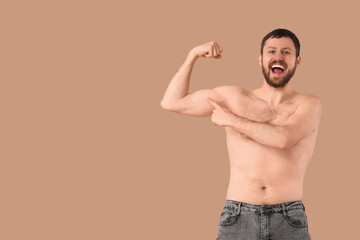 Man showing muscles on beige background. Body positive concept