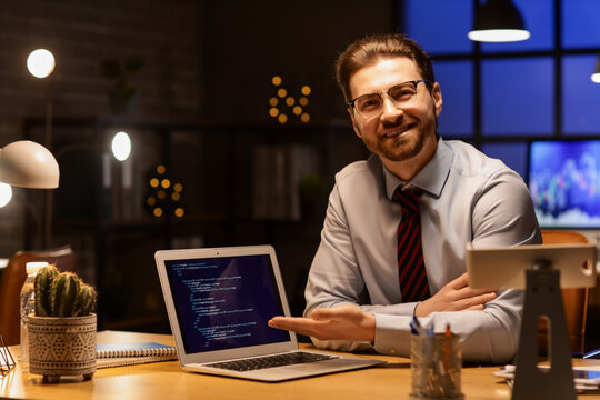 Handsome businessman working with laptop in office at night