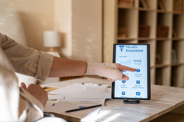Patient with wrist brace using digital tablet to manage health insurance claims and appointments...