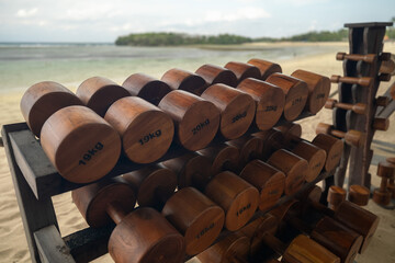 Sustainability wooden dumbbells on beach sand by the ocean. A symbol of sustainability, natural...