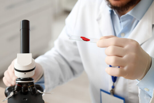 Male scientist with blood sample and microscope in laboratory, closeup - Powered by Adobe