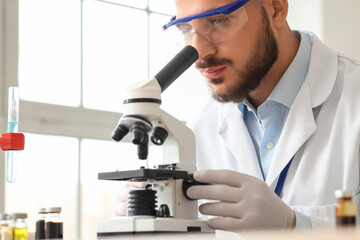 Male scientist looking through microscope in laboratory, closeup