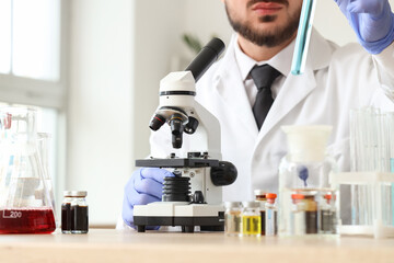 Male scientist with microscope working in laboratory, closeup
