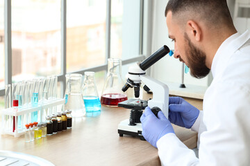 Male scientist looking through microscope in laboratory