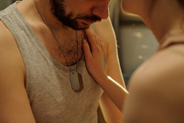 Man standing close to young adult woman touching his chest, both showing serious expressions,...