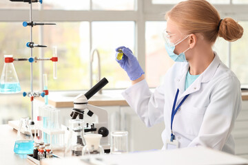 Female scientist with ampule and microscope working in laboratory
