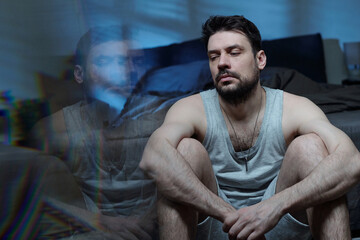 Caucasian young adult man looking away with tired expression reflecting in glass surface showing signs of stress and emotional struggle related to family problems