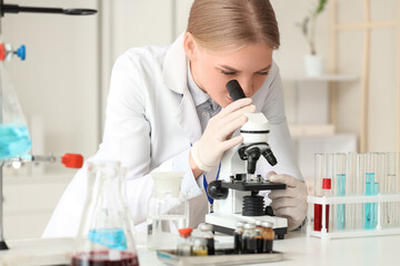Female scientist looking through microscope at table in laboratory
