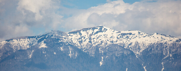 A mountain range covered in snow with a blue sky in the background