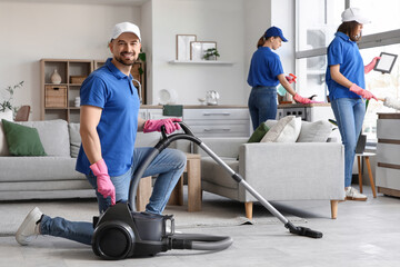 Male janitor using vacuum cleaner in room