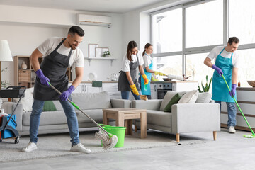 Team of young janitors cleaning in room