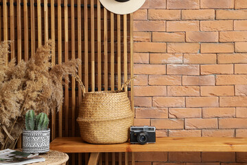 Wicker basket with photo camera on bench in hallway