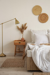 Interior of cozy room with soft linen on bed, table and lamp