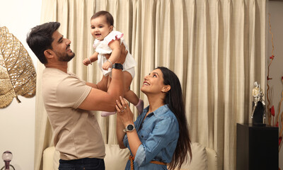  Indian young couple with one infant child sitting on home. Concept of Indian Happy Family Lifestyle 