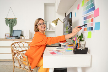 Female web designer working with color palettes at table in office