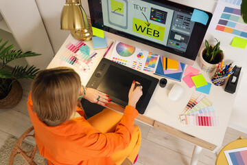 Female web designer working  graphic tablet at table in office, top view