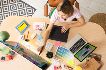 Female web designer working at table in office, top view
