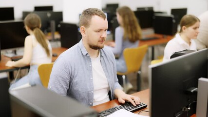  Man student of computer courses types on keyboard, performs work, educational practical task. Pupil performs educational tasks using computer