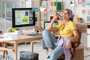 Beautiful web designer sitting at table in office