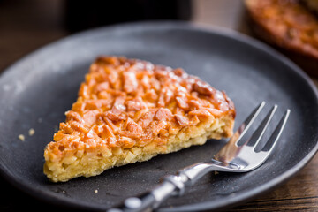 Sweet almond pie on plate on wooden table.