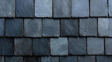 Close-up of a roof made up of dark blue slate tiles. the tiles are arranged in a grid-like pattern, with each tile slightly overlapping the one below it.
