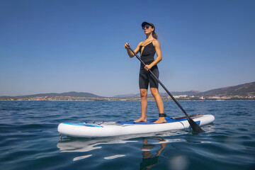 young women   riding  on sup surfing in the sea at sumer time