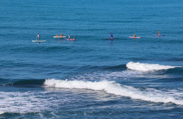 Company of young people  riding  on sup surfing in the sea at summer day