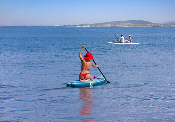 young women in red bikini  riding  on sup surfing in the sea at sumer time