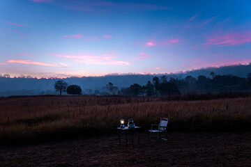 Fototapeta premium beautiful dusk or dawn landscape image showcases a vibrant twilight sky over a dry grassy field. Camping equipment,