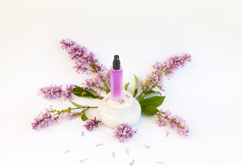 Frosted glass bottle of pink perfume with floral scent of lilac on round stone podium or pedestal...